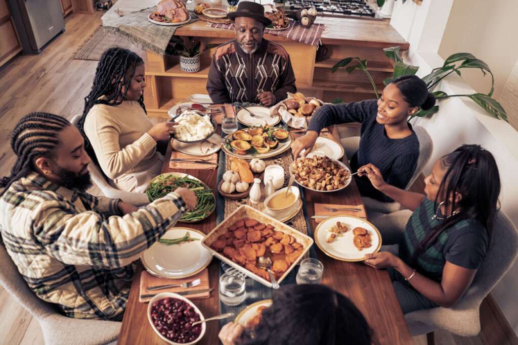 A Black family gathers together to cook and eat a Thanksgiving meal.