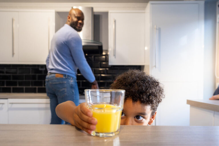 Young Boy Reaching for a Glass of Orange Juice