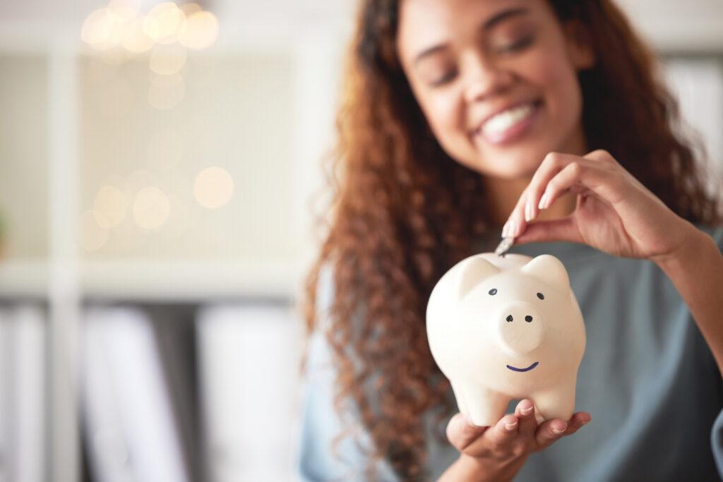 Young woman putting money in a piggy bank