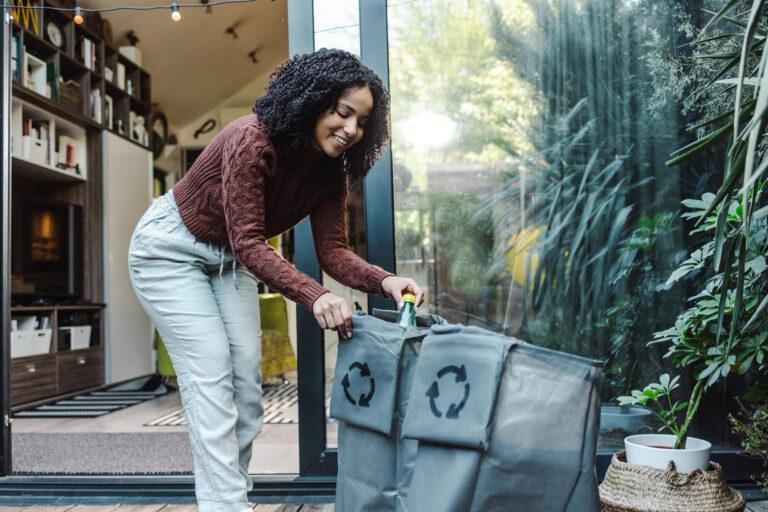 Woman sorts plastic recyclables outside of her home.