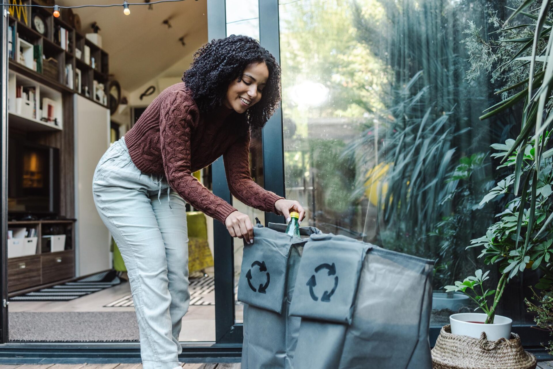 Woman sorts plastic recyclables outside of her home.
