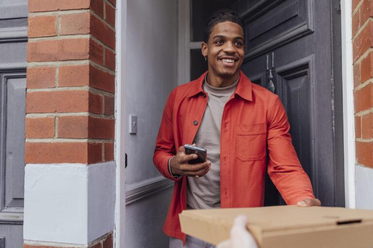 Young man accepting a food delivery at his front door.