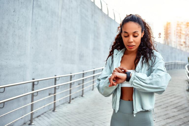 Woman on a run checking her smartwatch.